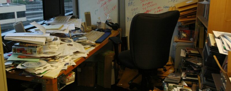 An extremely cluttered office with paper scattered everywhere.